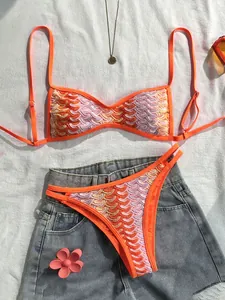Detailansicht eines Boho-Häkel-Bikinis mit orangefarbenem Fischschuppenmuster auf Denim.