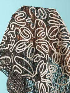 Close-up detail of black mesh bikini cover-up with white embroidered abstract patterns.