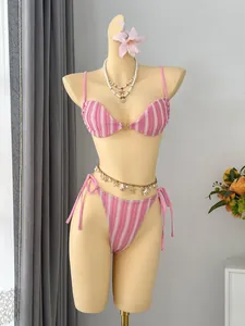 Nahaufnahme eines rosa gestreiften Bikinis mit Muschelkette auf einer Schaufensterpuppe.