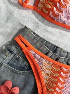 Detailansicht des orange-weißen Häkelmusters dieses Bikini-Sets im Bohème-Stil am Strand.