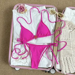 Felroze halterbikini-set met bloemaccent gepresenteerd in een stijlvolle reiskoffer