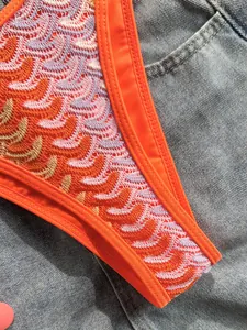 Nahaufnahme von bunten Häkel-Bikini-Mustern im Boho-Stil auf Denim-Hintergrund