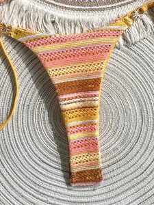 Macro view of colorful striped crochet bikini bottom with luxury golden hardware