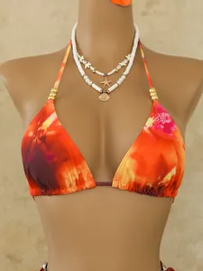 Detail van bohemian tie-dye bikinitop met gouden kralen en schelpenketting