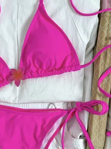 Gedetailleerd close-up beeld van een roze bikinitop met een decoratief bloemaccent