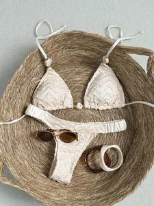 Close-up van een crème kanten bikini met marmeren kralen in een grote rieten mand