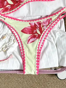 Nahaufnahme einer Vintage-Bikinihose mit Blumenmuster und rosa Zickzack-Stickerei im Koffer.