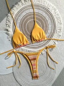 Detailed view of yellow and multi-color crochet striped bikini set on woven mats