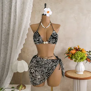 Stylish black and white patterned three-piece bikini set with matching beach sarong.