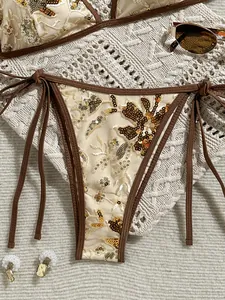 Primer plano de braguita de bikini de lentejuelas doradas con motivos florali y borde marrón
