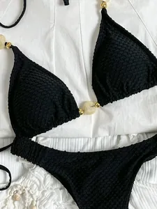 Macro view of black waffle textured halter bikini featuring elegant gold and marble beads
