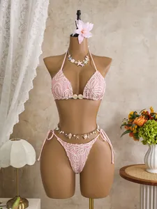 Detail of pink lace bikini with shell decorations and gold waist chain for beach resort.