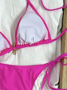 Gedetailleerd overzicht van een felle roze halterbikini met gouden bloemaccessoire