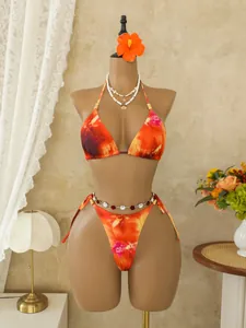 Gedetailleerd overzicht van een oranje bohemian bikini met bloemenprint en gouden kralen.