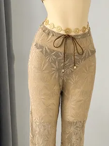 Detailed macro view of the intricate leaf pattern on mesh swimwear cover-up pants for women