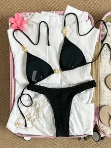 Close-up detail of sexy black textured bikini set featuring gold and pearl bead accents