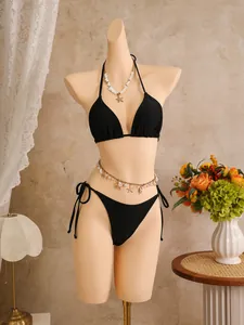 Klassieke zwarte halterbikiniset op een paspop met elegante strandaccessoires voor dames