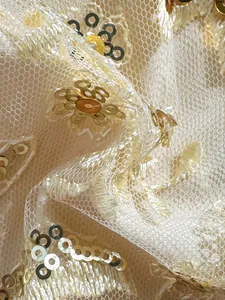 Detalle macro de un elegante bordado de lentejuelas oro champán sobre tela de malla fina