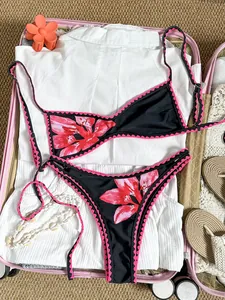 Retro-Bikini mit Blumenmuster und rosa Stickerei, präsentiert in einem Reisekoffer