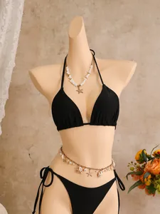 Detail van de schelpen heupketting en zeester ketting op een zwarte bikini badpak set
