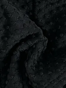 Close-up detail of black Swiss dot textured fabric for high-quality swimwear design