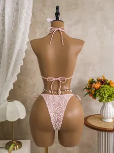 Close-up detail view of pink lace bikini back featuring decorative seashell waist chain