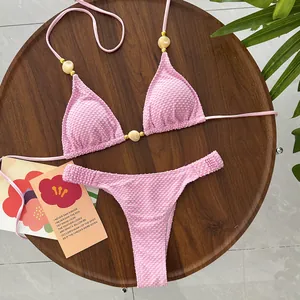 Close-up of pink textured bikini set with beaded halter neck straps on a wooden tray