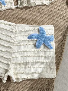 Gros plan d'un bas de bikini blanc texturé avec patch d'étoile de mer à paillettes bleues