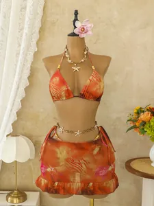 Detailopname van een bohemien oranje tie-dye 3-delige bikini met ruppelrok op een pop