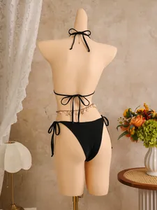 Gedetailleerd achteraanzicht van zwarte bikini met decoratieve schelpenketting voor zee