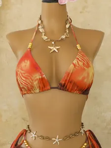 Detail van een boheemse bikini met oranje tijgerprint en bedeltjes van een zeester.