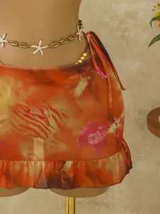 Detailopname van boheemse oranje bikini-rok met ruches en bloemenprint op mannequin