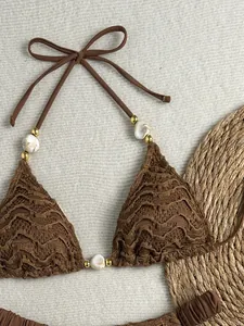 Detailopname van een bruine bikini-top met textuur, kralen en schelpaccenten.