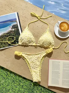 Bikini de dos piezas amarillo con bordado floral y encaje con café y revista de fondo.