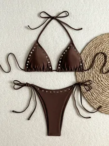 Detailed flat lay of brown two-piece bikini with silver rivet studs and string ties