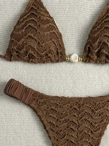 Detailweergave van bruine getextureerde bikini met gouden kralen en wit stenen sieraad