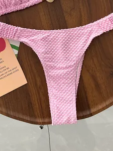 Macro view showing the pink popcorn textured fabric of a high cut bikini bottom