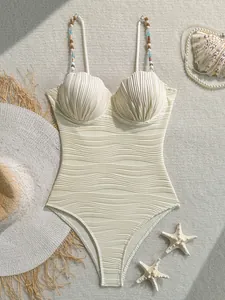 Elegante bañador crema con textura ondulada, copas de concha y tiras de cuentas