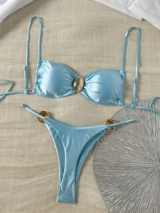 Glänzendes hellblaues Bikini-Set mit goldenen Details auf strukturiertem Hintergrund.
