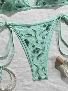 Vista detallada de una braguita de bikini verde menta con lentejuelas florales y lazos laterales