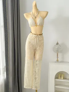 Detailed view of cream three-piece bikini set with leaf lace beach trousers on mannequin.