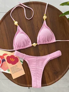 Macro view of pink bubble textured bikini featuring decorative beige beads on wooden tray