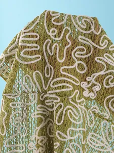 Macro view of green crochet mesh beach cover-up with abstract white line embroidery
