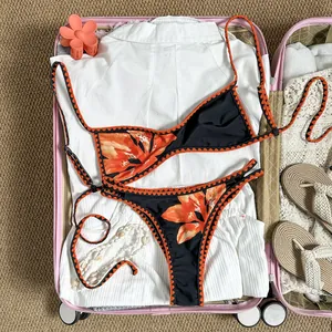 Zweiteiliger Bikini mit Blumenstickerei im rosa Koffer mit Urlaubsaccessoires präsentiert.