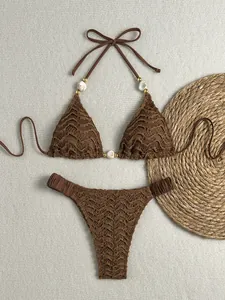 Close-up van bruine getextureerde bikini met elegante parelaccenten en halternekontwerp