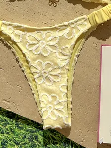 Primer plano detallado de la parte inferior del bikini amarillo con bordado floral blanco