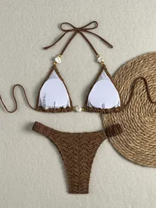 Detailopname van een bruine bikini met structuur, kralen en schelpversieringen