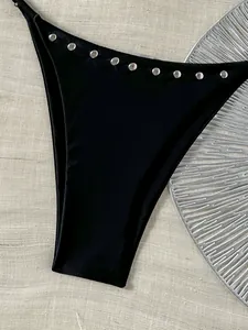 Detail van zwart bikinibroekje met zilveren klinknagels voor strandvakantie.
