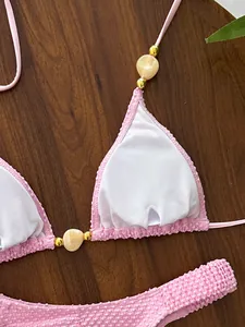 Detail view of pink textured halter bikini with gold beads and white lining