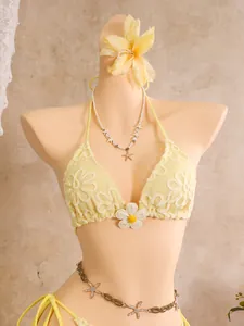 Detailansicht eines gelben Bikini-Oberteils mit Blumenstickerei und 3D-Blütenapplikation